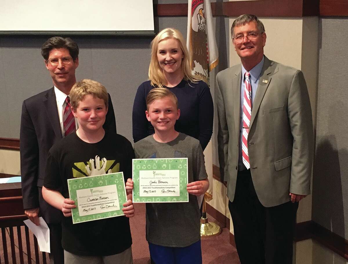 Chairman Kurt Prenzler, Resource Education Program Coordinator Eve Drueke and County Board member Phil Chapman present Jake Benson and Camden Boeser of Worden Elementey School with a certificate of recognition for the Trashformation competition.