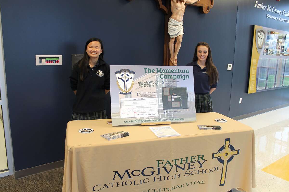 Freshman Faith Scott, left, and junior Amaree Moss welcomed guests Tuesday night to Father McGivney Catholic High School's Open House and Media Night.