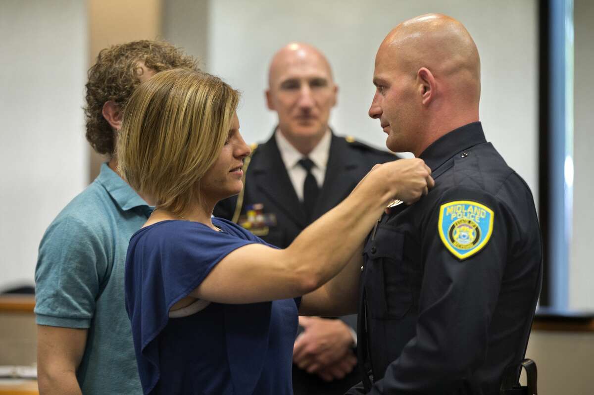 Aubrea Burchfield pins a badge on her husband James Burchfield II as their son Anthony Burchfield and Midland Police Chief Cliff Block look on during an officer swearing-in ceremony at City Hall Wednesday afternoon. Burchfield, was joined by Jose DeLeon and Christopher Hurst as new officers to the City of Midland Police Department.