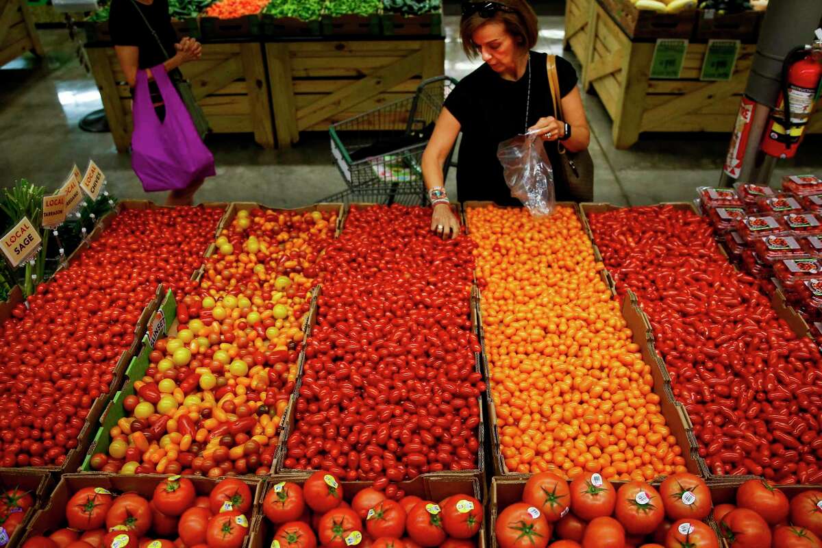 Monica Llobet grabs a handful of tomatoes at Central Market, which underwent a $10 million renovation that was completed this month.