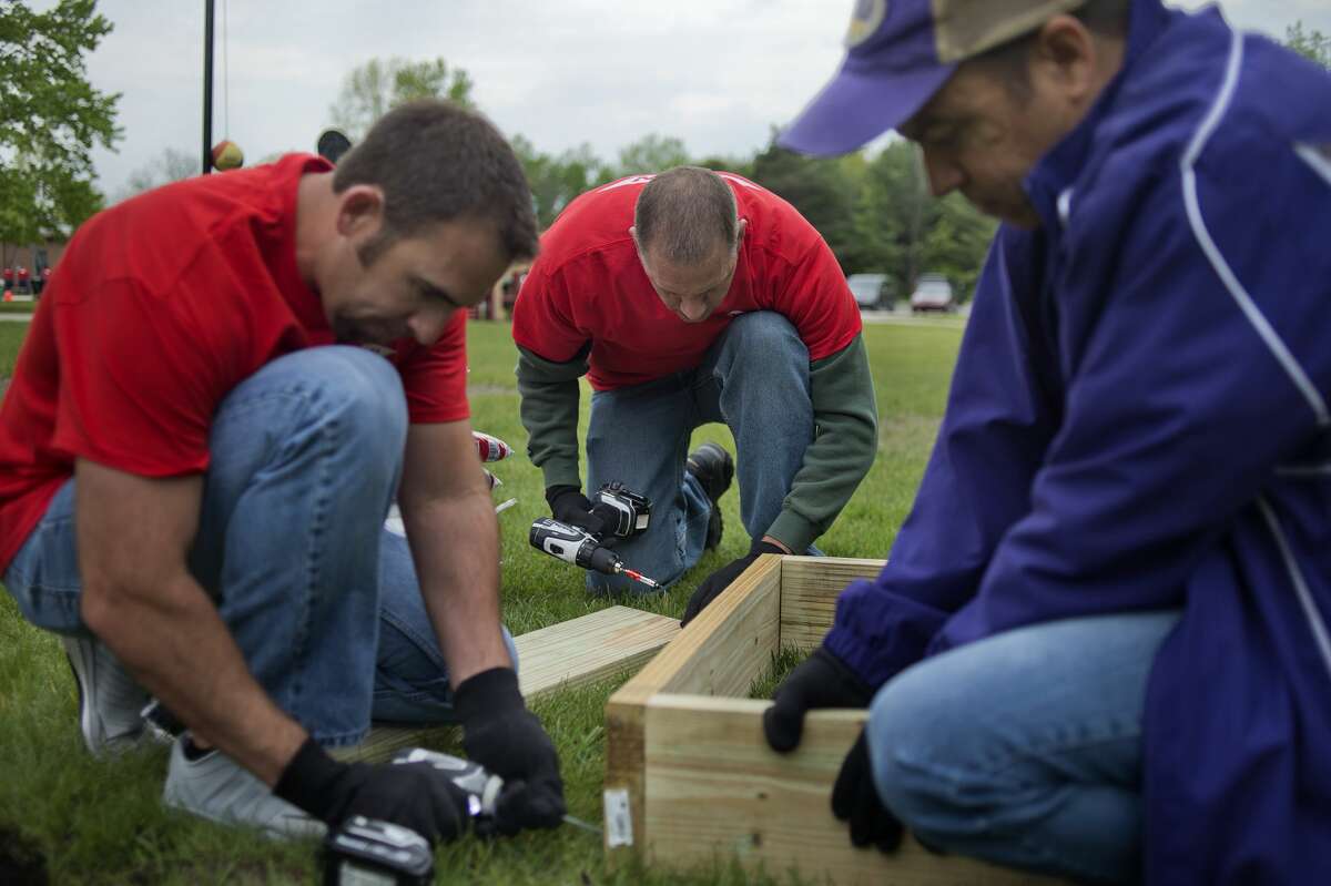 The Dow Chemical Co. employees from left: Rustin St. Amant, Scott Martin and John Touchard build a garden box at Floyd Elementary Wednesday evening. Approximately 100 Dow employees and Floyd Elementary staff mulched gardens, planted fruit trees and built garden boxes for the school.