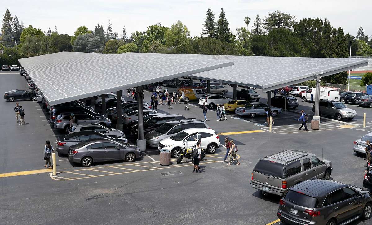 Students walk to their cars parked below solar panel arrays during the lunch break at Los Altos High School in Los Altos, Calif. on Wednesday, May 24, 2017. Some state officials are hoping that a financial incentive program, similar to the solar panel rebates offered to homeowners, would spark growth in the battery industry and lower costs.
