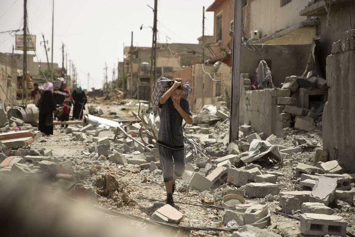 An Iraqi boy carries heavy belongings through rubble as he flees fighting between Iraqi special forces and Islamic State militants, in western Mosul, Iraq, Monday, May 15, 2017. (AP Photo/Maya Alleruzzo)