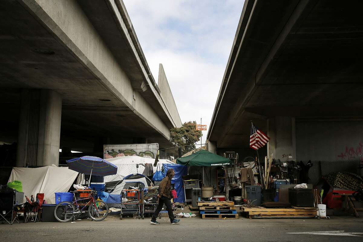 A man, who only gave his first name as Jim, walks back to his encampment after grabbing his friends cigarette lighter near Brush and 6th streets on Thursday, May 25, 2017, in Oakland, Calif. They're seen the encampment grown to more than a couple dozen people in the last four years.