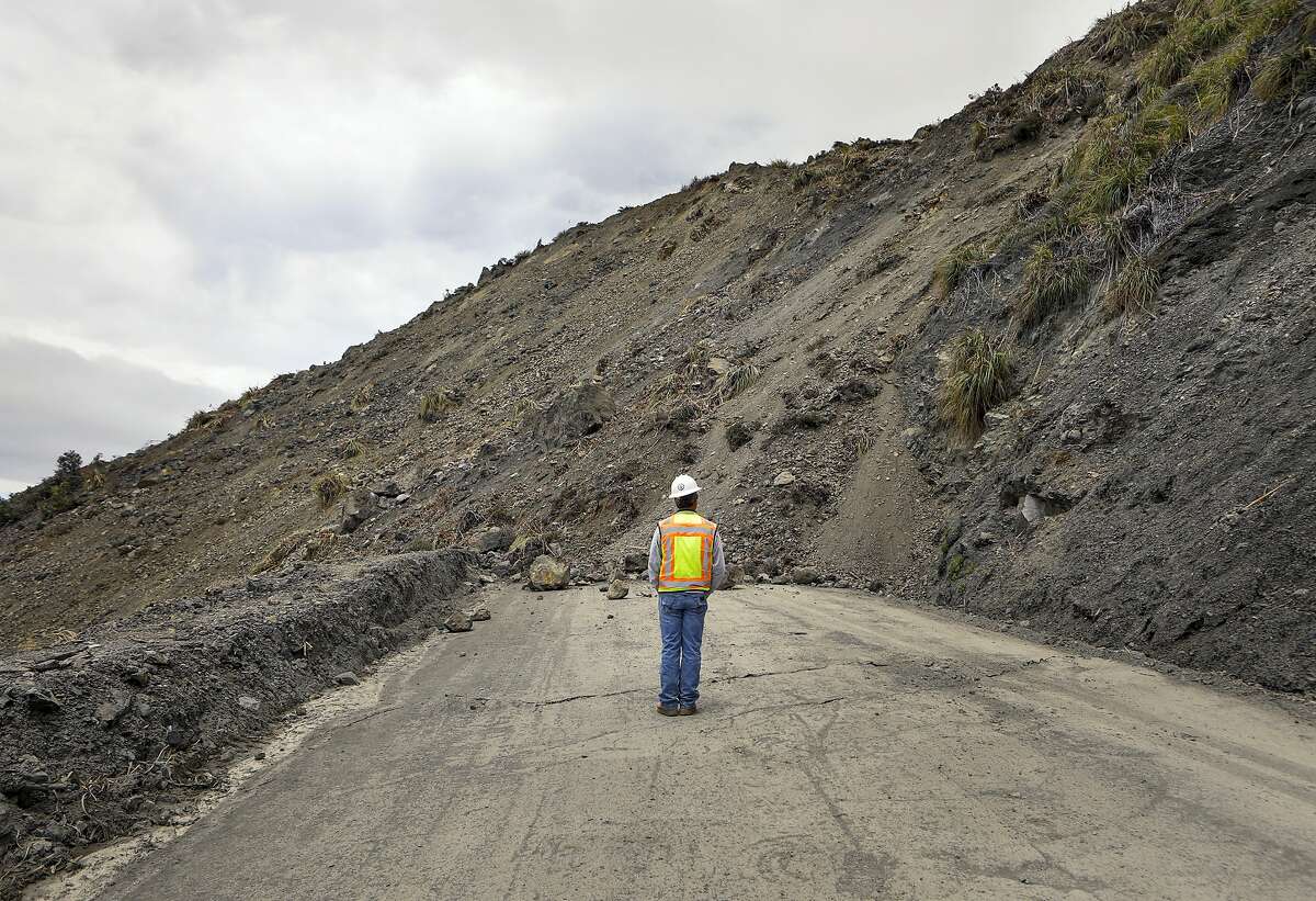 Bret Haney, construction inspector with Caltrans, looks at the south side of a landslide on Wednesday, May 24, 2017, after a massive slide went into the Pacific Ocean over the weekend in Big Sur, Calif. The slide buried a portion of Highway 1 under a 40-foot layer of rock and dirt and changed the coastline below to include what now looks like a rounded skirt hem, Susana Cruz, a spokeswoman with the California Department of Transportation, said Tuesday. (Joe Johnston/The Tribune (of San Luis Obispo) via AP)