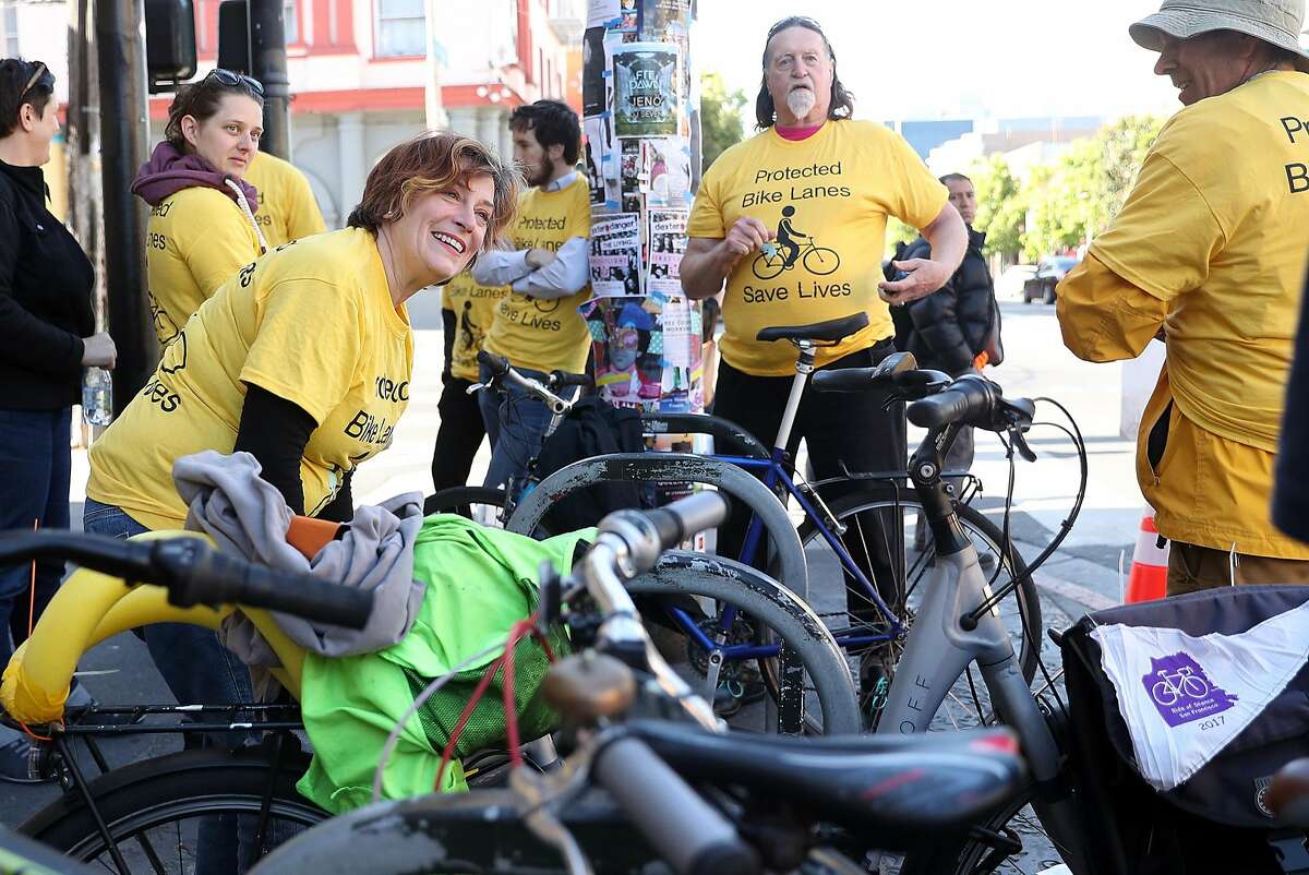 Movement founder Maureen Persico (left) greets fellow San Francisco bike riders before the group created a human chain to separate the bike lane from the car lane on Valencia Street in San Francisco, Calif., on Thursday, May 25, 2017.
