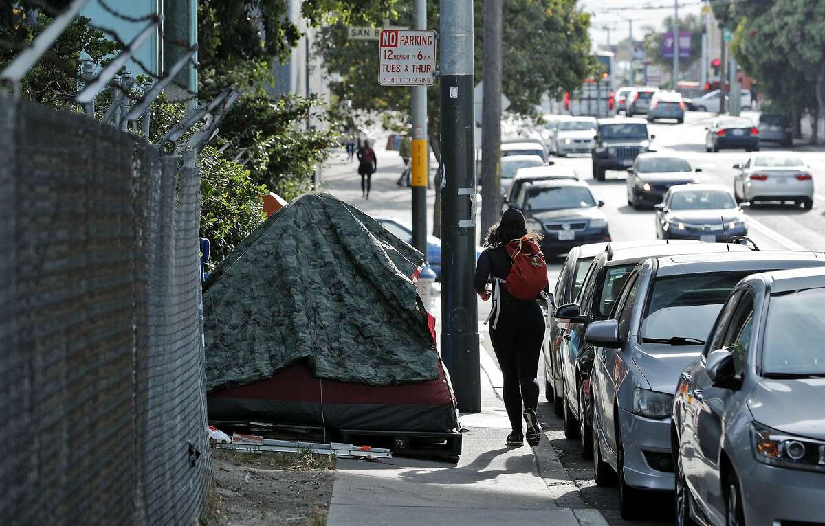Pedestrians walk around tents in a homeless encampment underneath Highway 280 in Potrero Hill in San Francisco, Calif., on Wednesday, May 24, 2017. Resident nearby believe encampments a couple of blocks away from their home have gotten immeasurably worse over the past year despite so much attention on homelessness at City Hall.