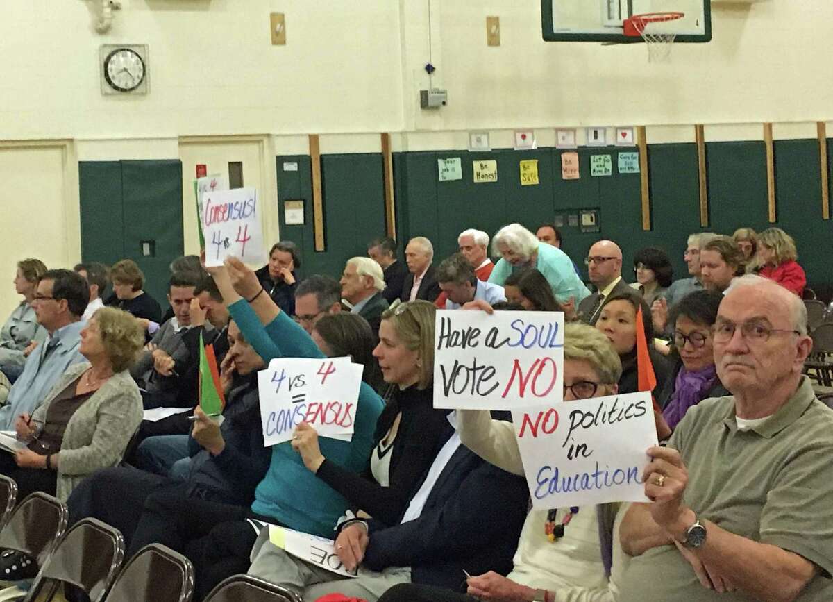 Community members brought signs to Thursday's school board meeting, indicating their opinions on the proposal to change the Board of Education's election structure.