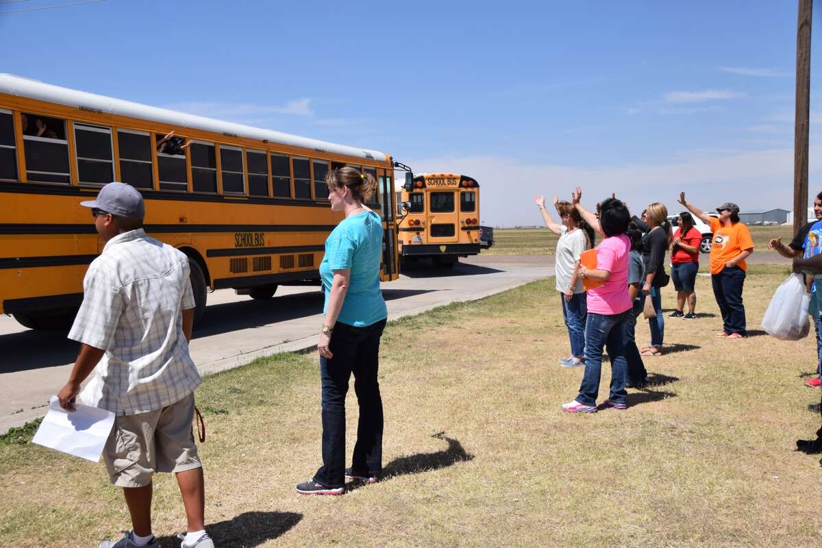 Teachers and staff of Hillcrest Elementary wave goodbye as school buses loaded with students pull away from the campus Thursday on the last day of school. A sincere wave goodbye at the start of summer vacation is a longstanding tradition at the school.