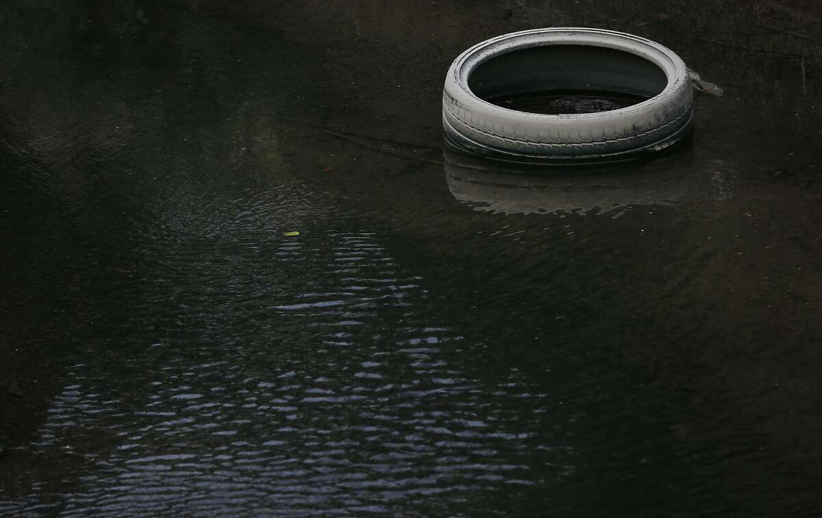 A car tire sits in Lion Creek, which empties into Damon Slough May 26, 2017 in Oakland, Calif.