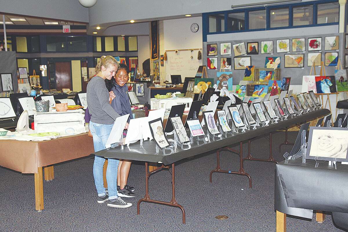   From left, Bad Axe seniors Maggie Ingram and Cher Sophannarat share a smile as they gaze over the hundreds of pieces of artwork featured at this year’s Bad Axe Art Show.