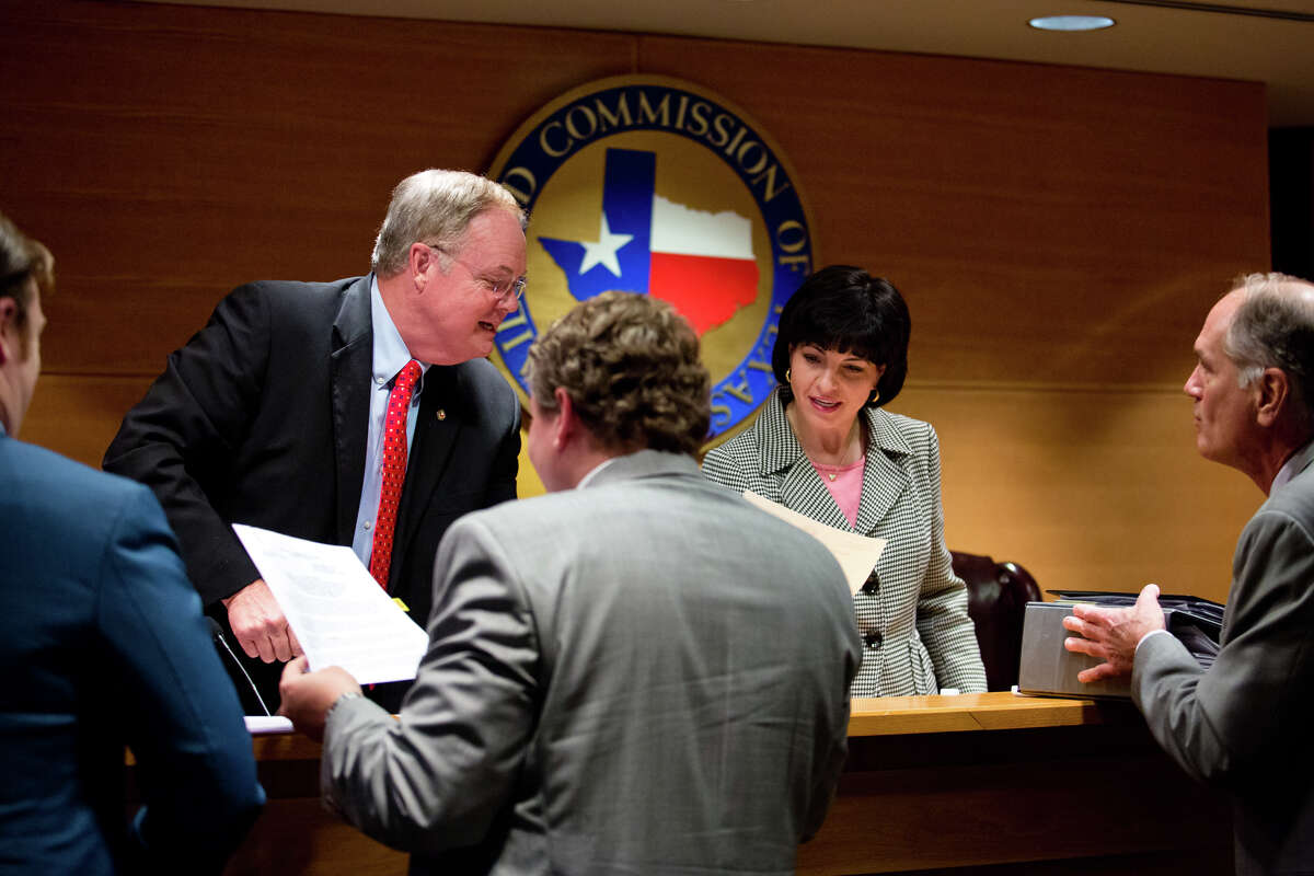 Commissioner Wayne Christian and Chairman Christi Craddick sign ﻿orders after a Texas Railroad Commission conference this month. 