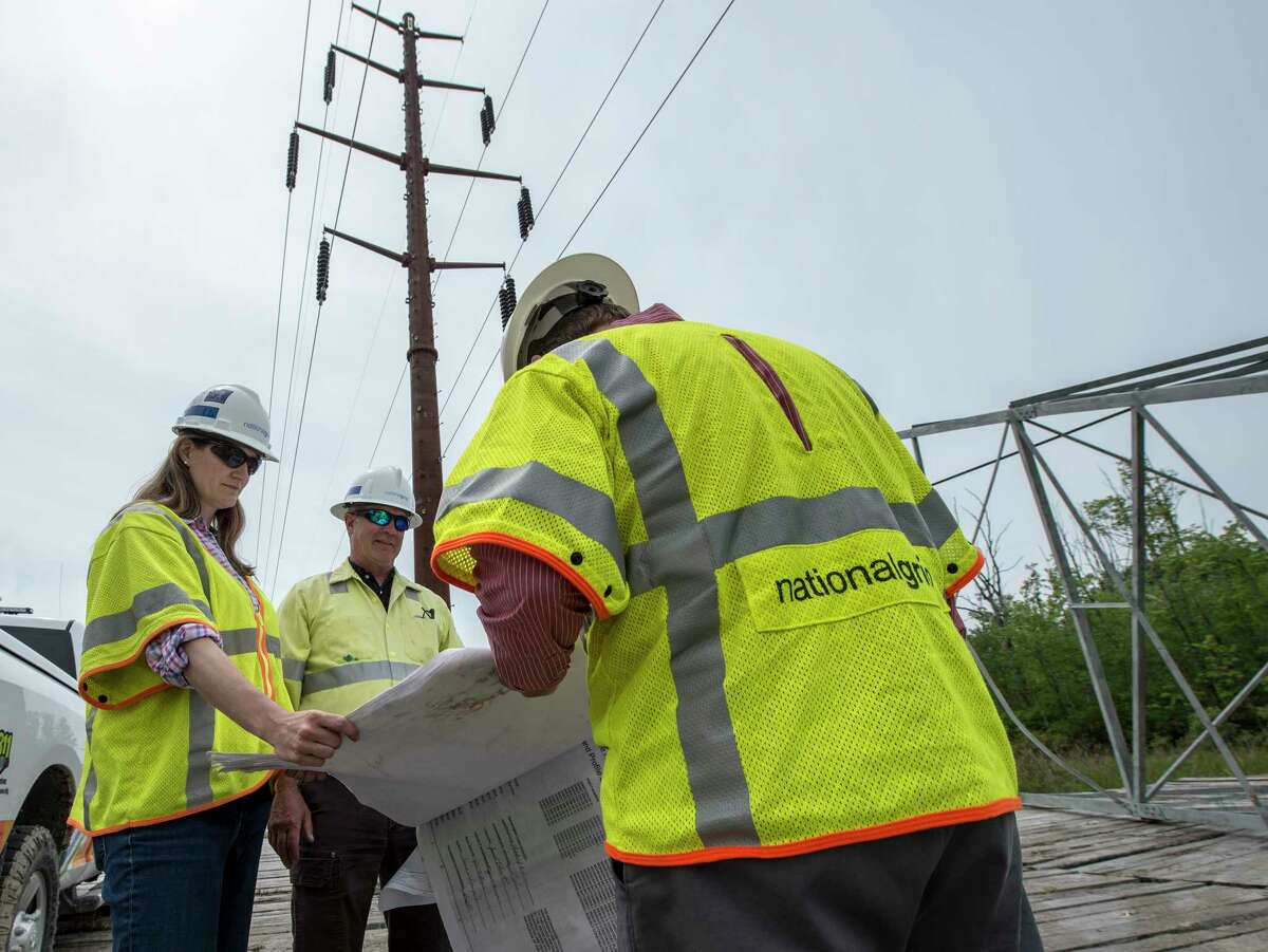 National Grid workers; Jennifer Schlegel, project manager , left George Breen, construction supervisor, center and Patrick Stella, communications look over plans for the new cable and weathering steel uprights at the new construction on the power line upgrade by National Grid on Paterson Road in Tuesday May 23, in Greenwich, N.Y. (Skip Dickstein/Times Union)