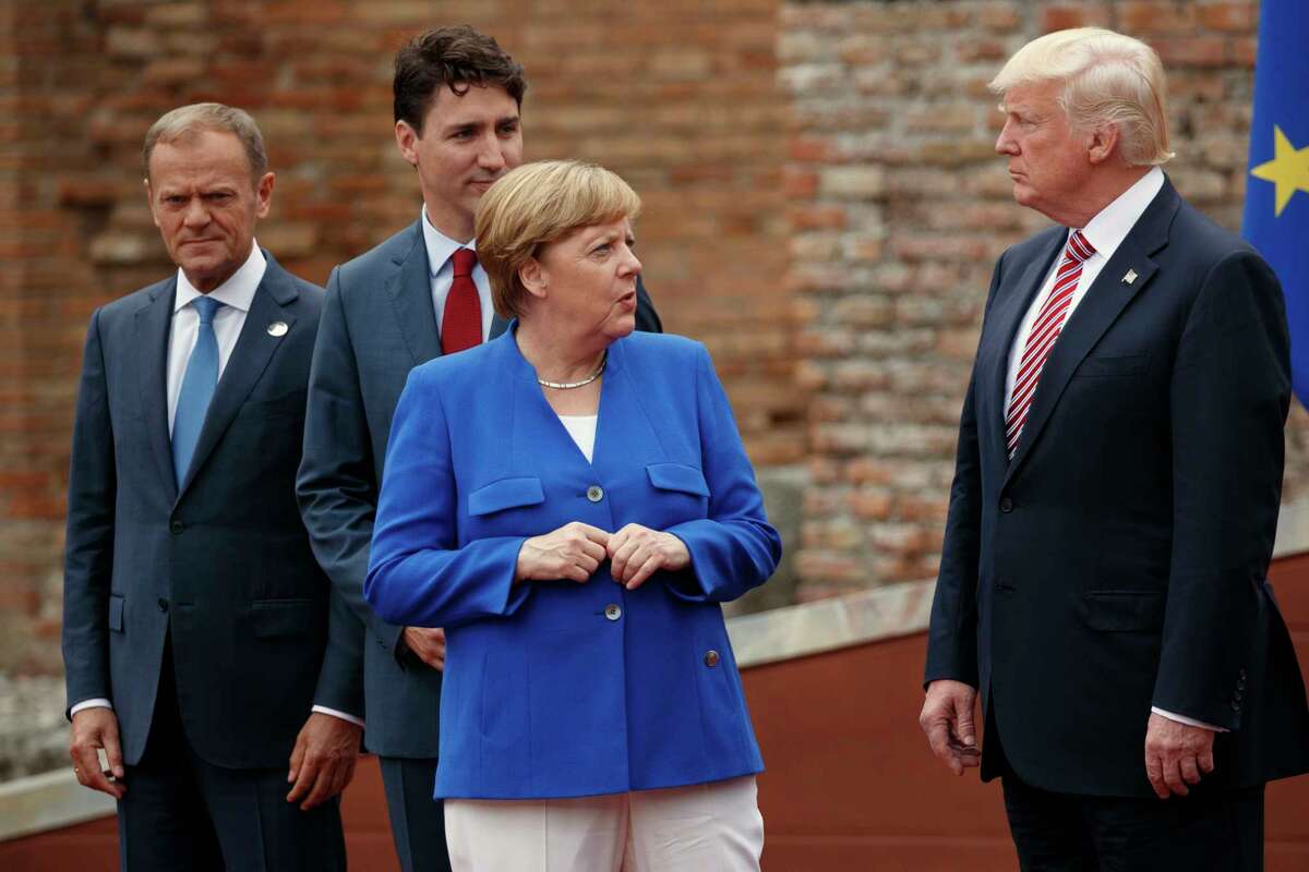 German Chancellor Angela Merkel talks with President Donald Trump during a family photo with G7 leaders at the Ancient Greek Theater of Taormina, during the G7 Summit, Friday, May 26, 2017, in Taormina, Italy. From left, European Council President Donald Tusk, Canadian Prime Minister Justin Trudeau, Merkel, and Trump. (AP Photo/Evan Vucci)