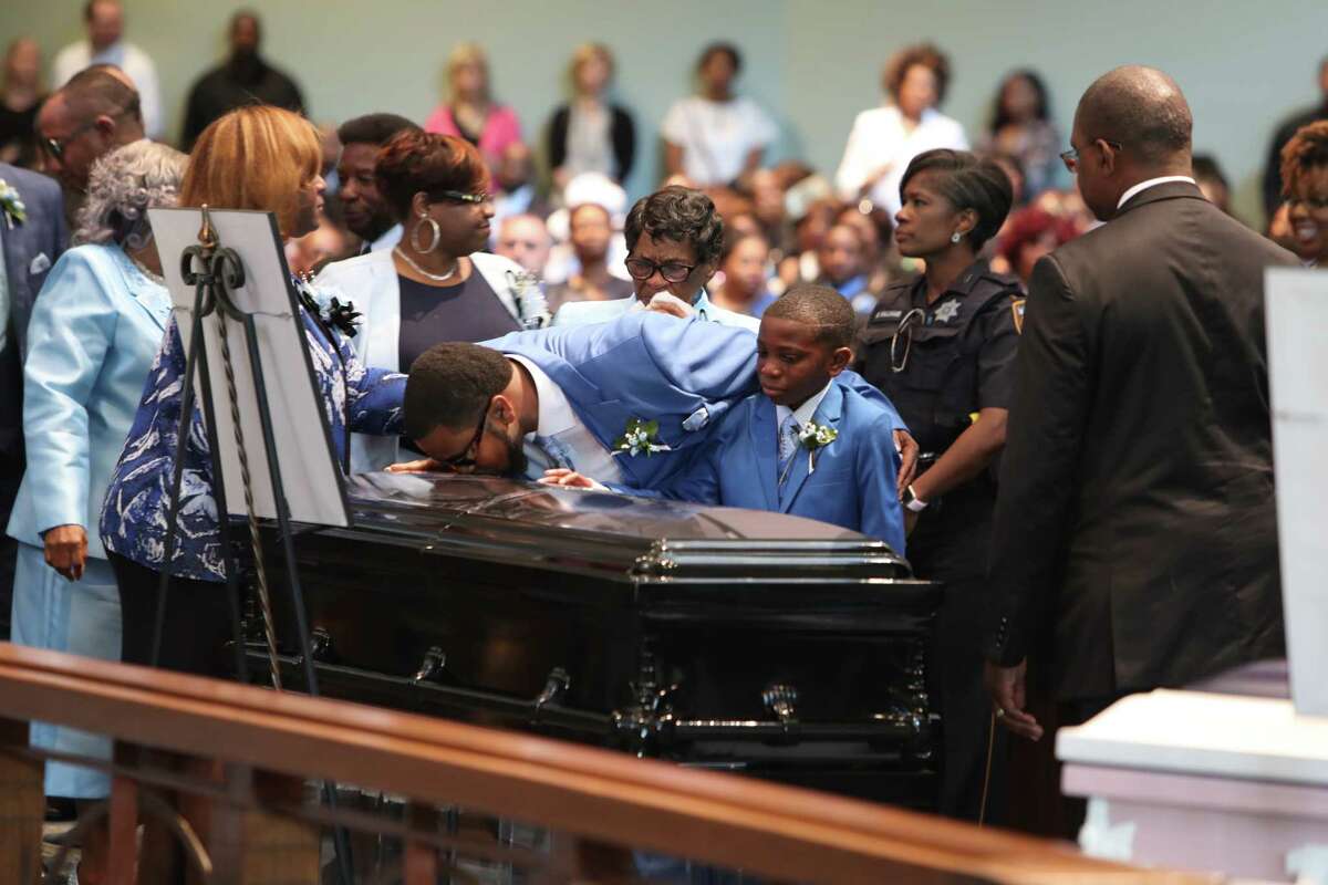 Adrian Mitchell (right) watches his father, Terrance Mitchell Sr., kiss one of the 3 caskets of his siblings, Terrance, Kaila and Kyle funeral. (Steve Gonzales / Chronicle)