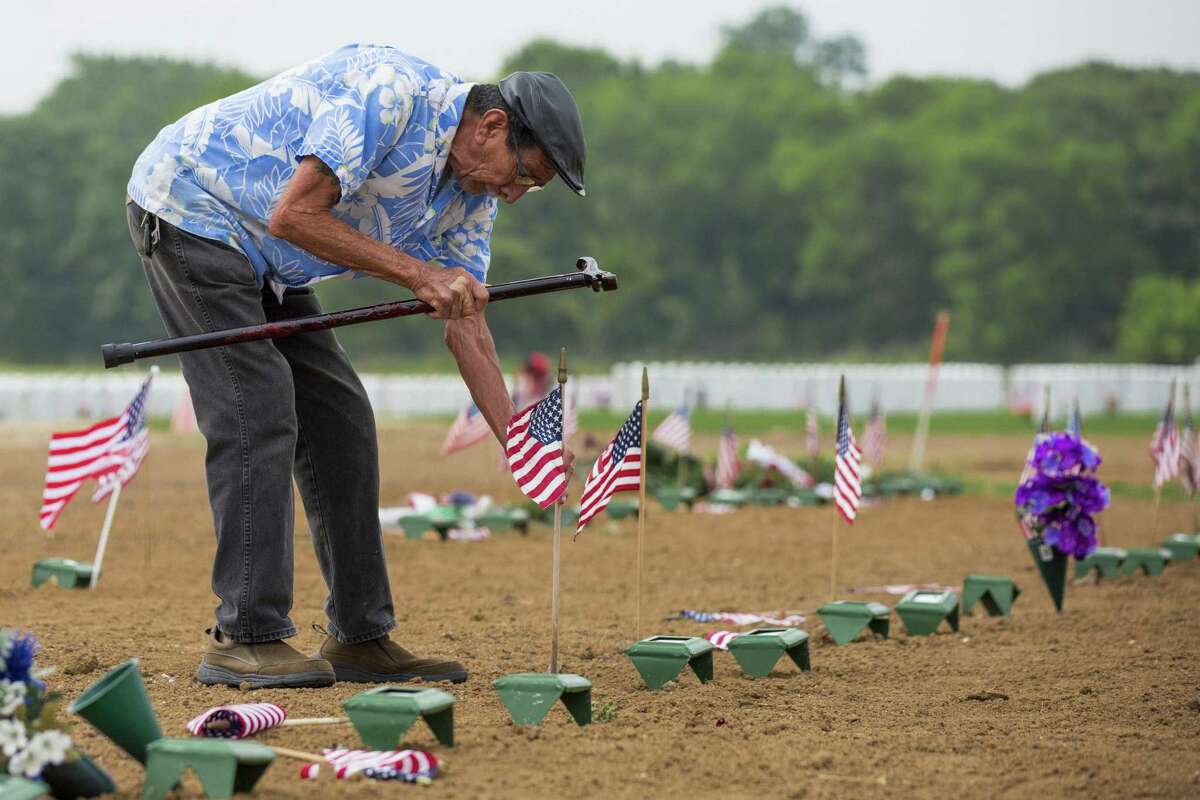 Phillip Suarez, a Marine Corps veteran, uses his cane to tap in an American flag that had fallen over in front of the temporary grave marker for his brother-in-law Genaro Rincon in the section of Fort Sam Houston National Cemetery where recently deceased veterans are interred. Rincon, who was interred May 9, was one of the more than 2400 names the American Legion read aloud at Fort Sam Houston National Cemetery in San Antonio, Texas on May 27, 2017. Ray Whitehouse / for the San Antonio Express-News
