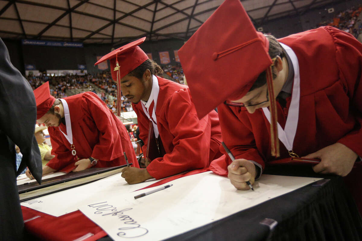Graduates sign their names after receiving their diplomas during the Caney Creek High School commencement ceremony on Saturday, May 27, 2017, at Sam Houston State University.