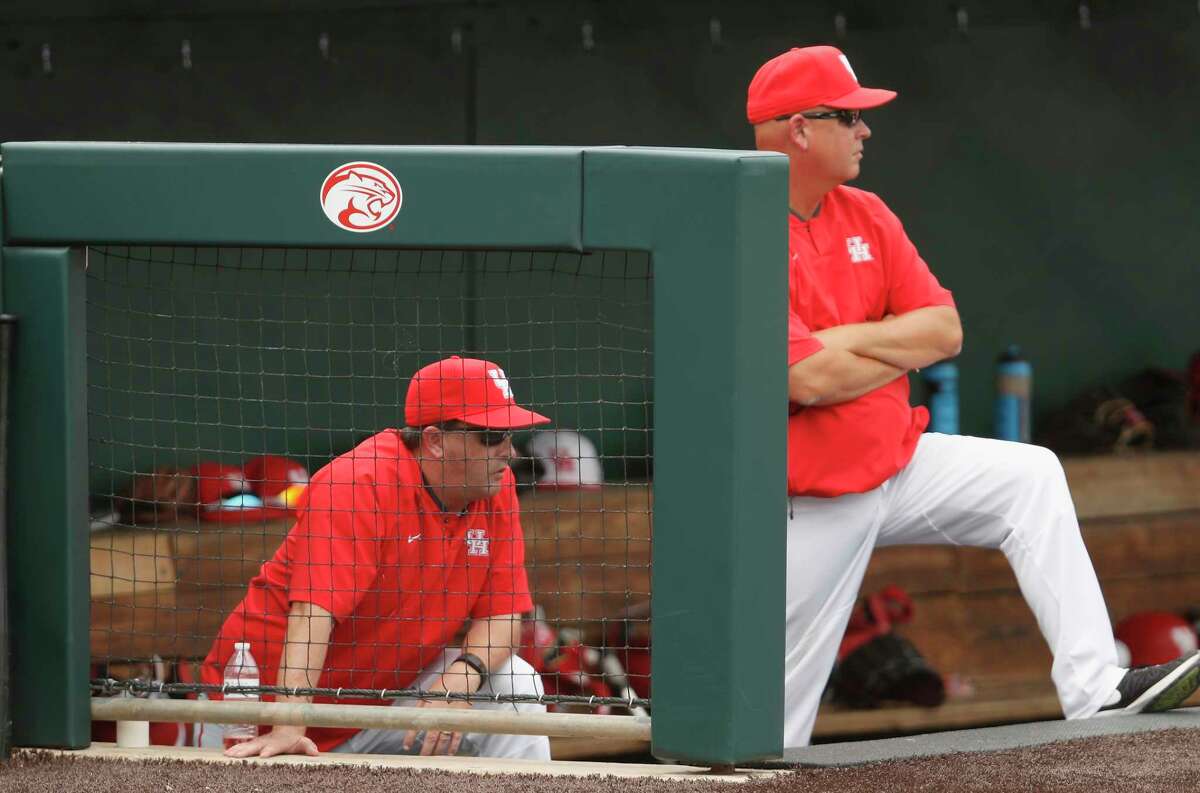 Houston head coach Todd Whitting (left) and assistant coach Trip Couch watch from the steps of the dugout during the NCAA baseball game 