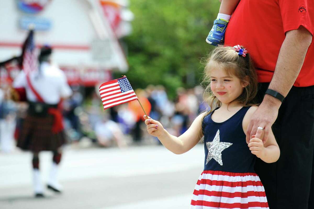 Zoe Paksi, 4, of Stamford, waves an American flag while watching bagpipers march on Summer Street during the Memorial Day Parade in Stamford on Sunday.