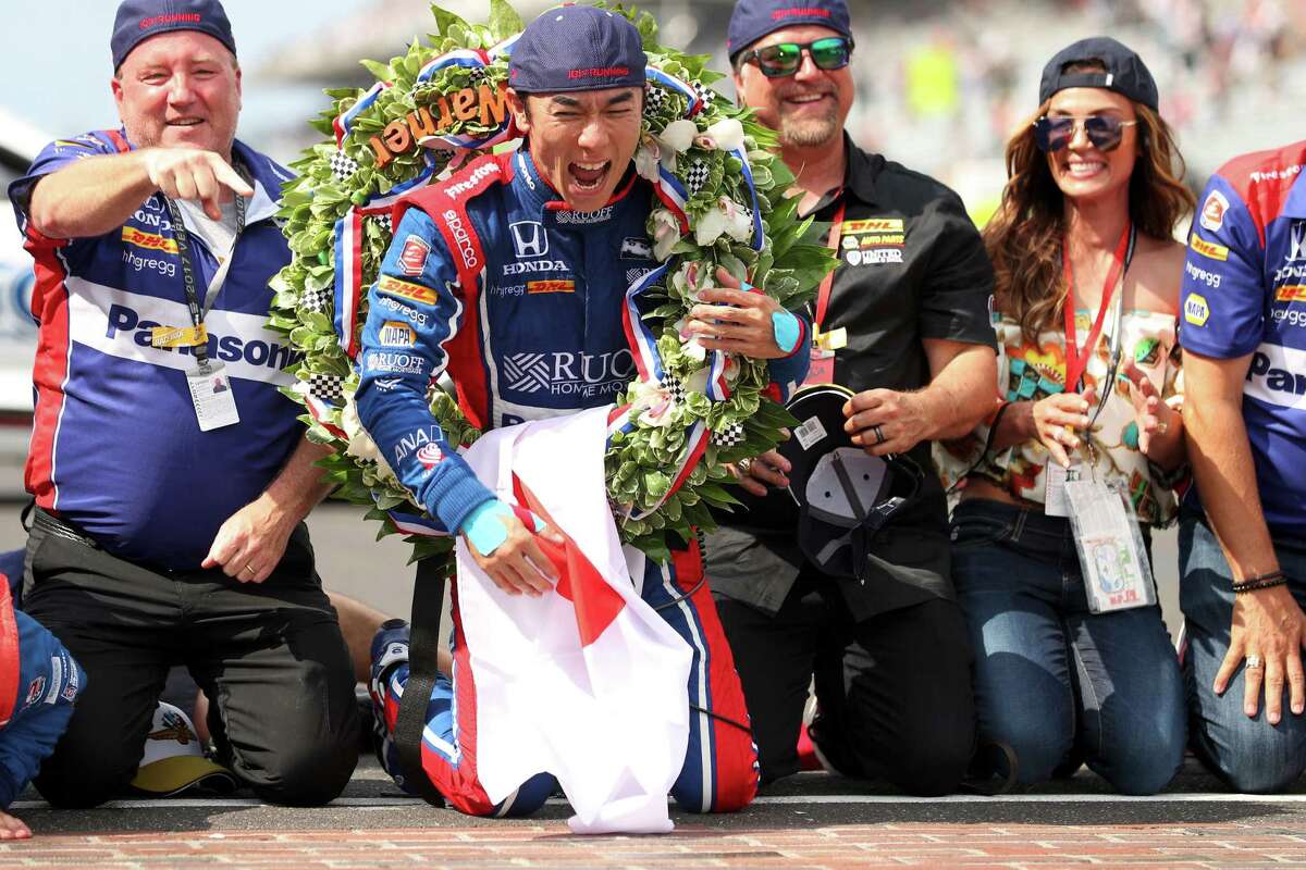 With team owner Michael Andretti, right, looking on, Indianapolis 500 winner Takuma Sato is all smiles after kissing the brick inlay at the finish line.