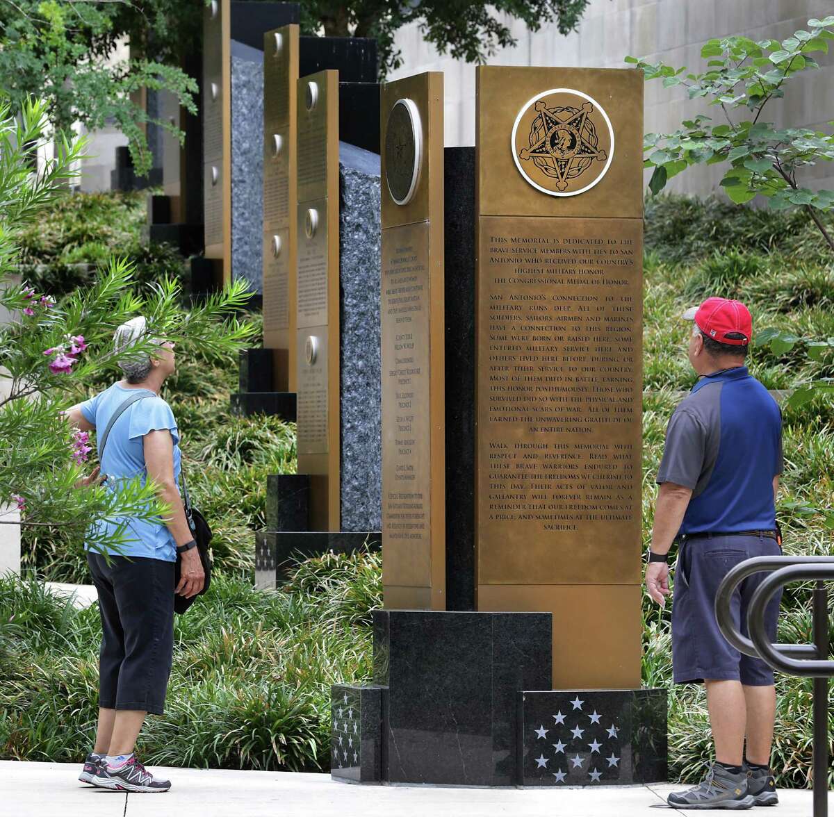 A couple stops and reads the inscriptions on the Medal of Honor Portal on the Riverwalk near the Tobin Center for the Performing Arts, one of many military monuments in San Antonio.