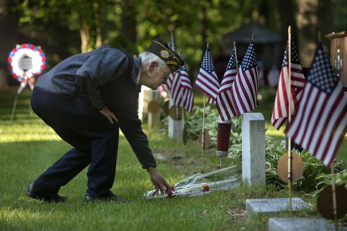 David Patrick with the Veterans of Foreign Wars Chemical City Post 3651 places a red carnation on a grave during a service at the Midland Cemetery on Memorial Day.