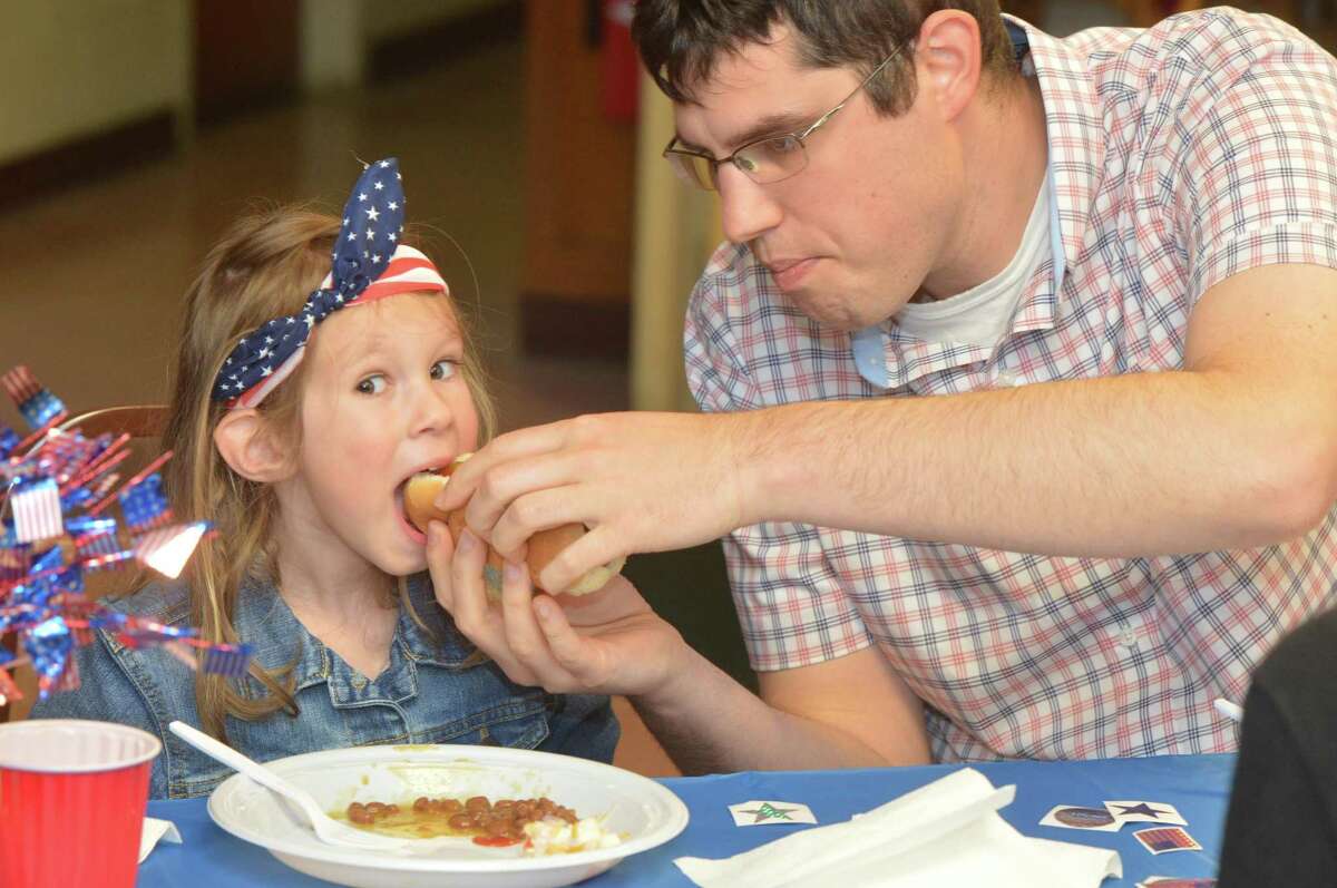 Four-year-old Adeline Waldmiller, great granddaughter of Grand Marshal Henry Simon, and grandson Matthew Waldmiller enjoy some hot dogs during lunch at the American Legion Post 12 on Monday. The traditional lunch is served at the post after the parade, but the parade was canceled due to bad weather.