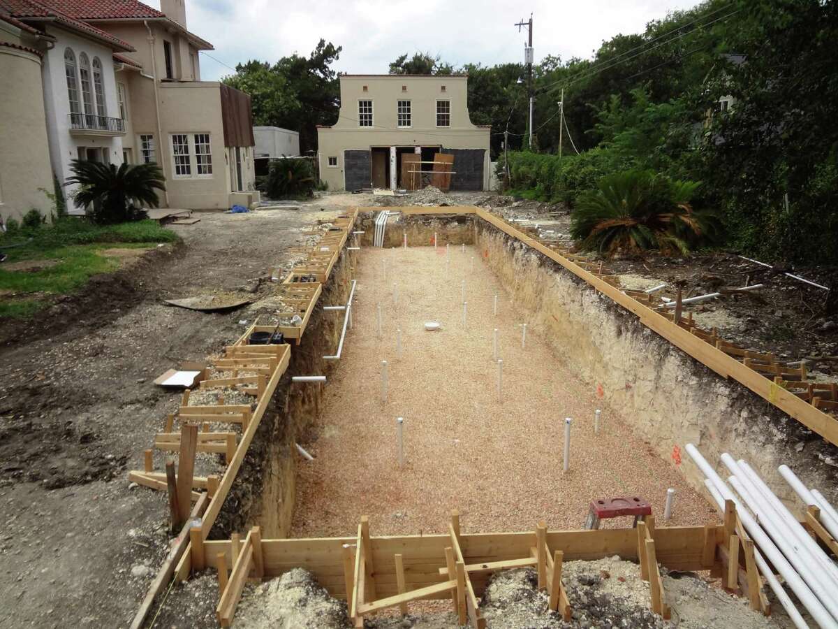 The backyard lap pool is 75 feet long by 16 feet wide. Builders didn’t have to go far underground before encountering caliche. The former garage at the end of the pool will be the new poolhouse with a media room. The Tres Robles house is on the left.