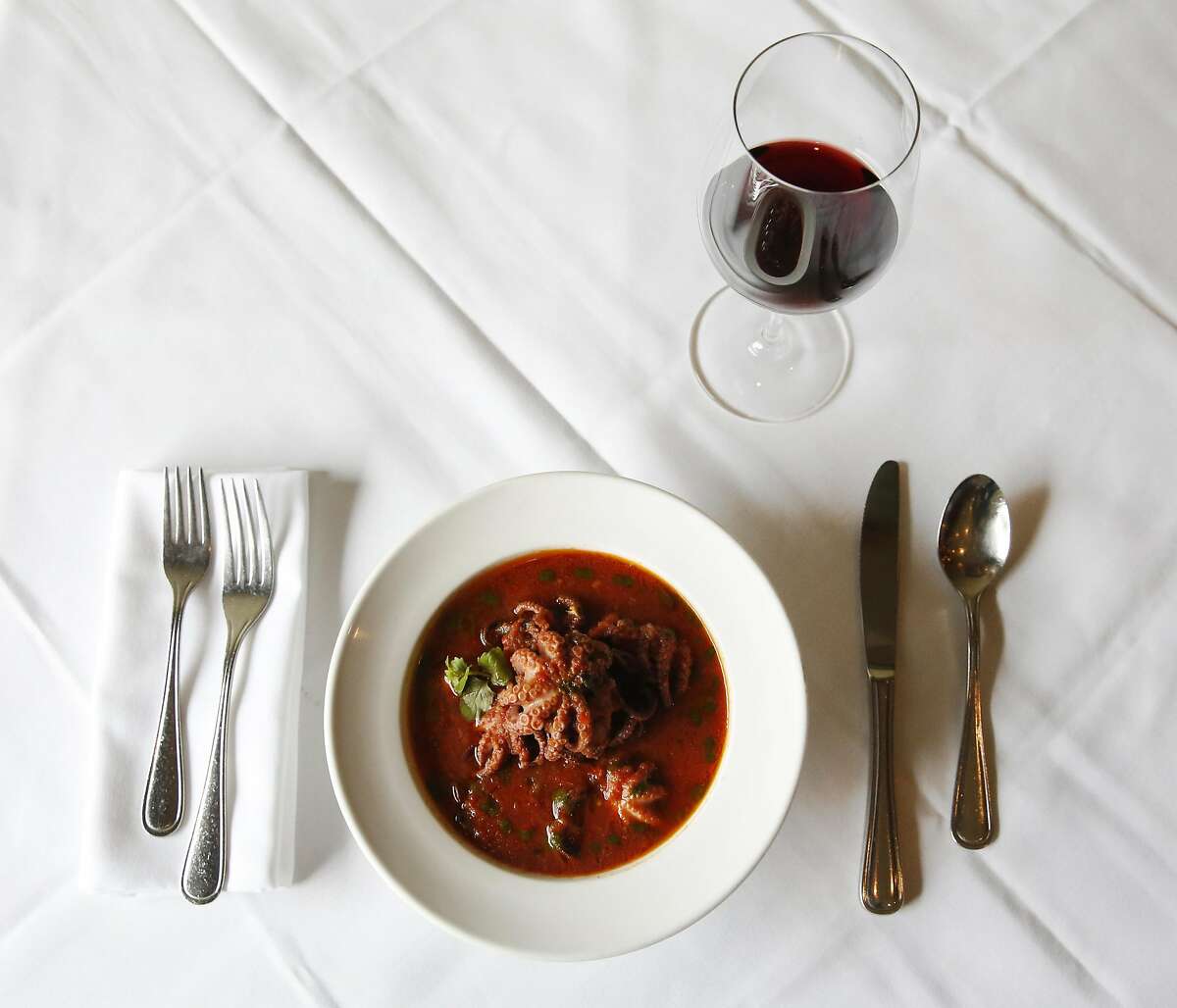 A glass of Is Solus, Carignano del Sulcis with Prupisceddu in Umidu cun Tomatiga (baby octopus stew in a spicy tomato sauce) pictured at La Ciccia May 26, 2017 in San Francisco, Calif.