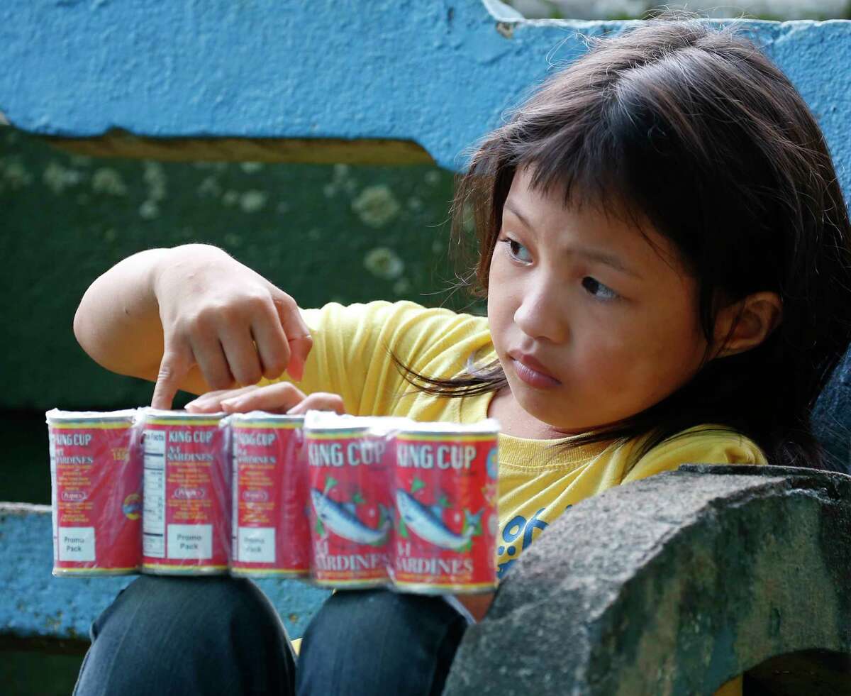 A displaced girl holds a supply of sardines at an evacuation center on Wednesday.﻿ Tens of thousands of residents are now housed in evacuation centers. ﻿