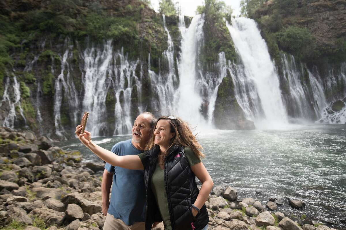 Lois Navarro takes a photo with her dad, Raul, at the Burney Falls on Tuesday, May 30 2017, Burney, CA. Burney Falls water comes from underground springs above and at the falls, which are 129 feet high, and provides an almost constant flow rate even during the dry summer months. Tuesday, May 30 2017, Burney, CA. The falls were called "the Eighth Wonder of the World" by President Theodore Roosevelt