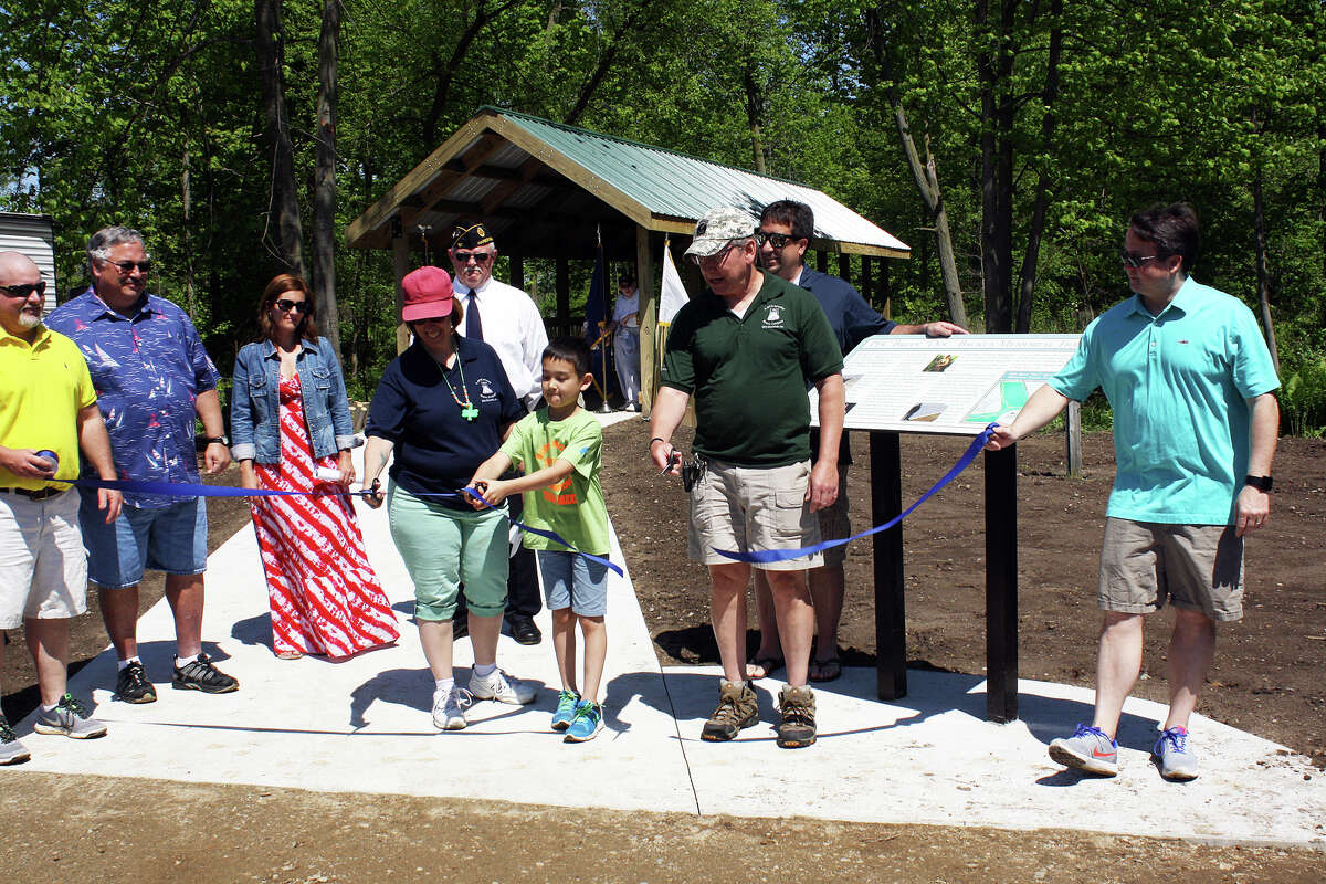   PFC Backus’ mother, Ann, son Jack, and dad Al, cut the trail’s ribbon