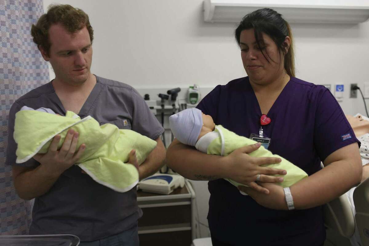 License Vocational Nurse students Norman Ryan-Waldo, left, and Ruby Cigarroa practice carrying newborns during a lab at St. Philip's College May 31, 2017. Cigarroa is a Project QUEST student. The program provides a model others should examine.