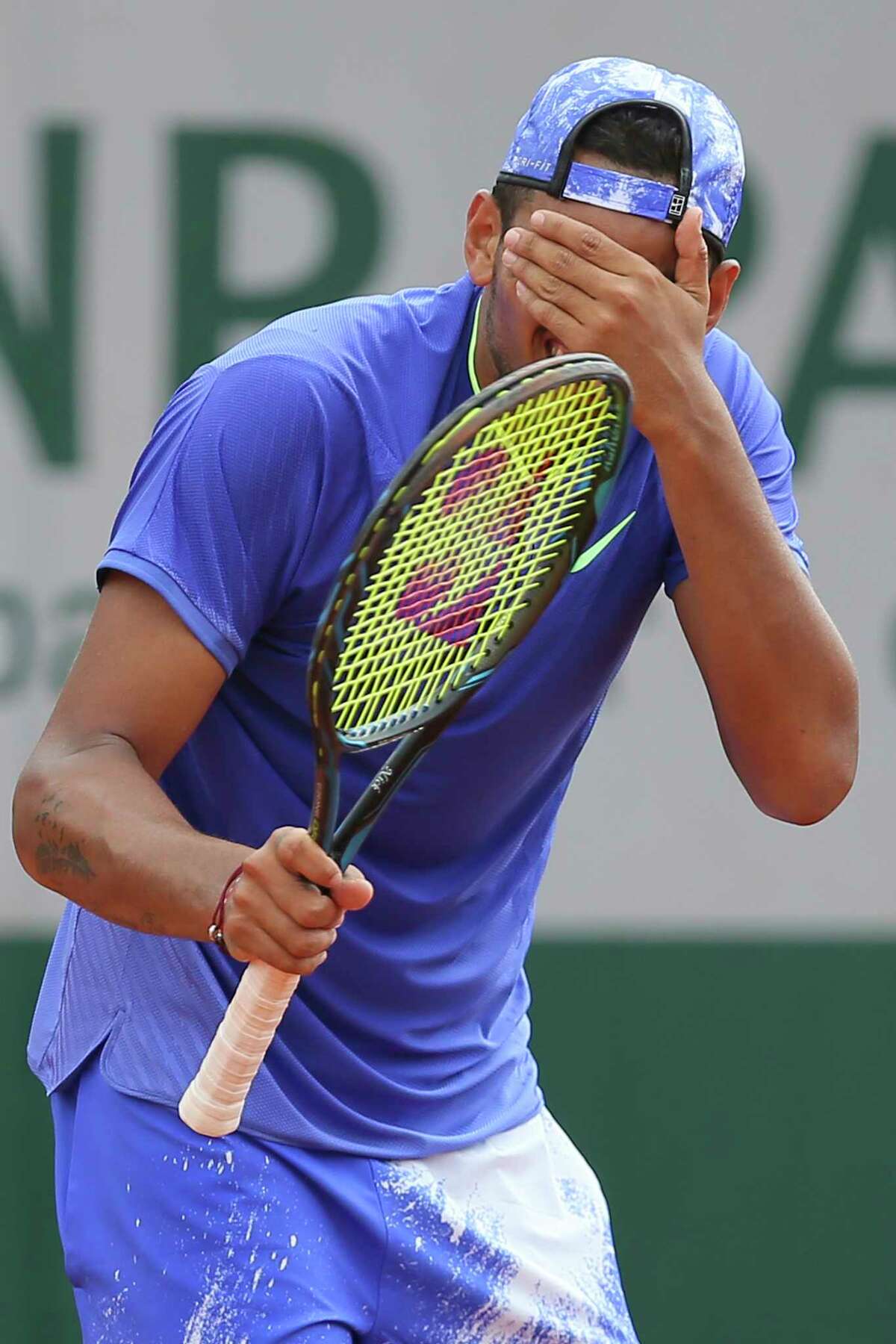Australian Nick Kyrgios can't bear to watch what he's about to do to his racket after missing a shot and eventually losing a set Thursday at the French Open.