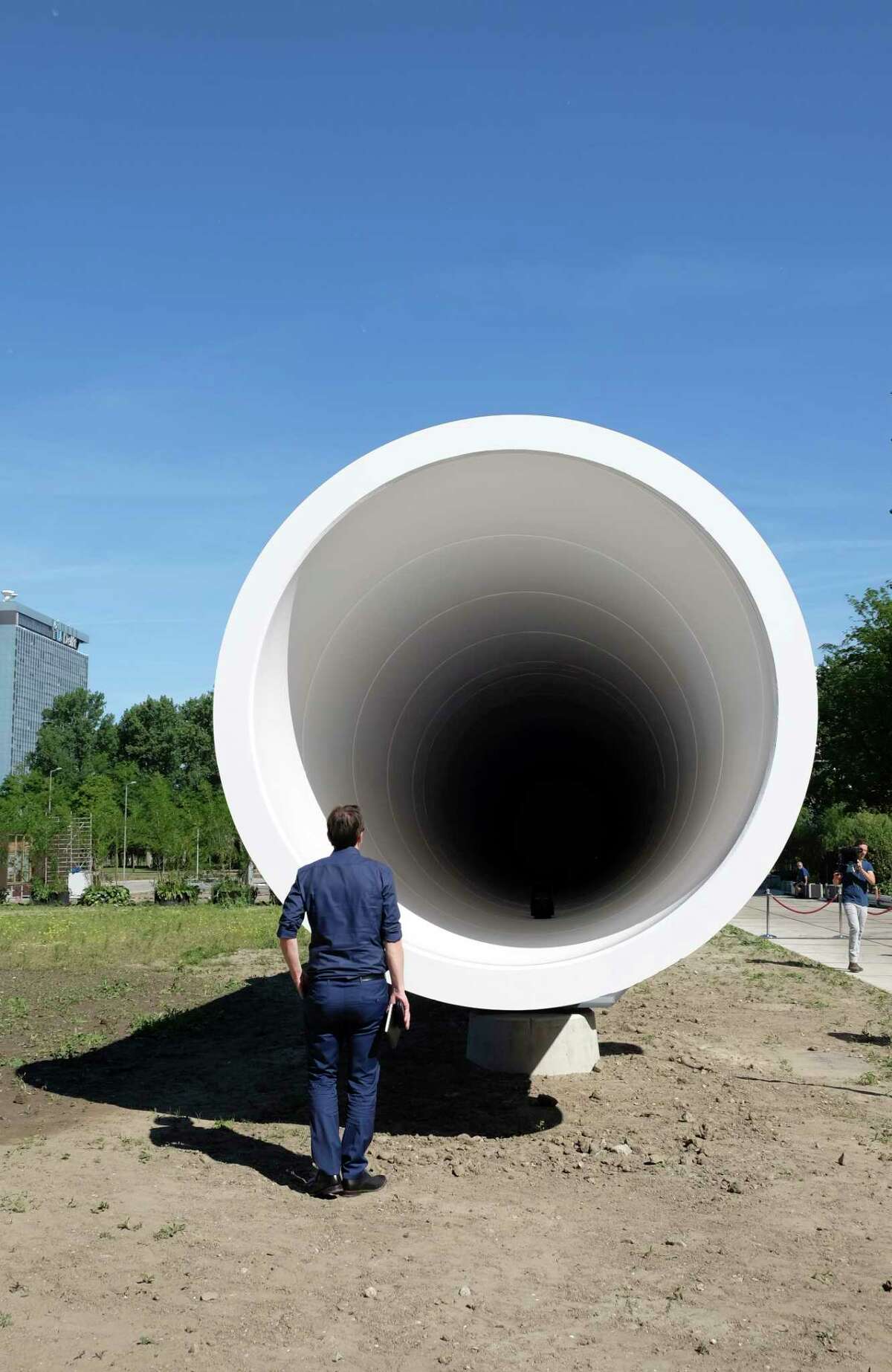 A man looks at a hyperloop test facility unveiled by a tech startup and a construction company in Delft, Netherlands, Thursday, June 1, 2017. The 30 meter (100 foot) long white steel tube will be used to help develop the futuristic high-speed transportation system. The tube is a first step toward developing the system in the Netherlands, a key European transportation transport hub. (AP Photo/Mike Corder)