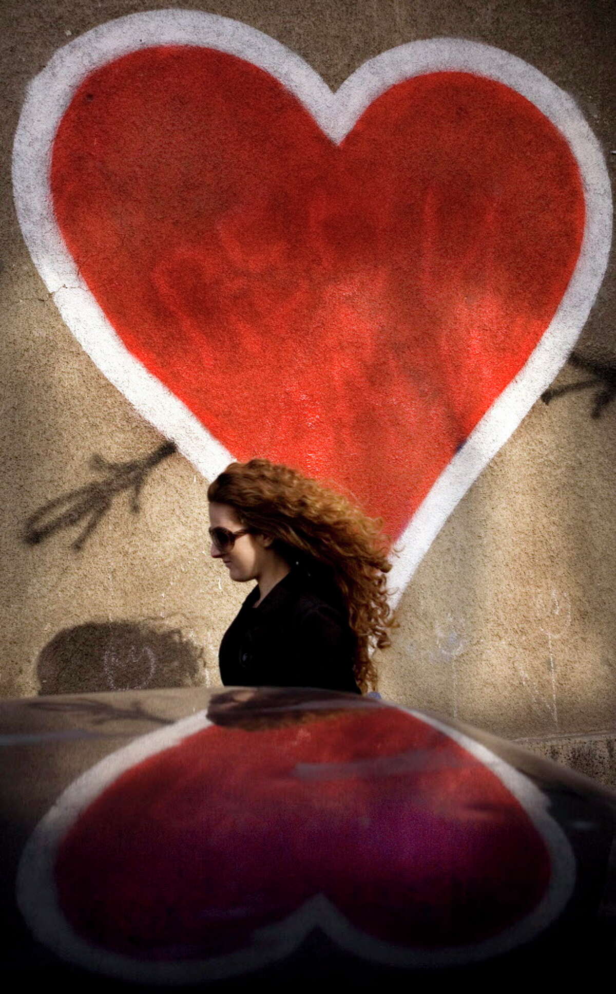A woman passes a large Valentine's hearts drawn on a wall in the Bulgarian capital of Sofia. Bulgarians, who traditionally celebrate grape growing and wine making feastivals on Feb. 14, have begun to also mark Valentine's Day since the Communist rule collapsed in the Balkan country in 1989. (AP Photo/Valentina Petrova)