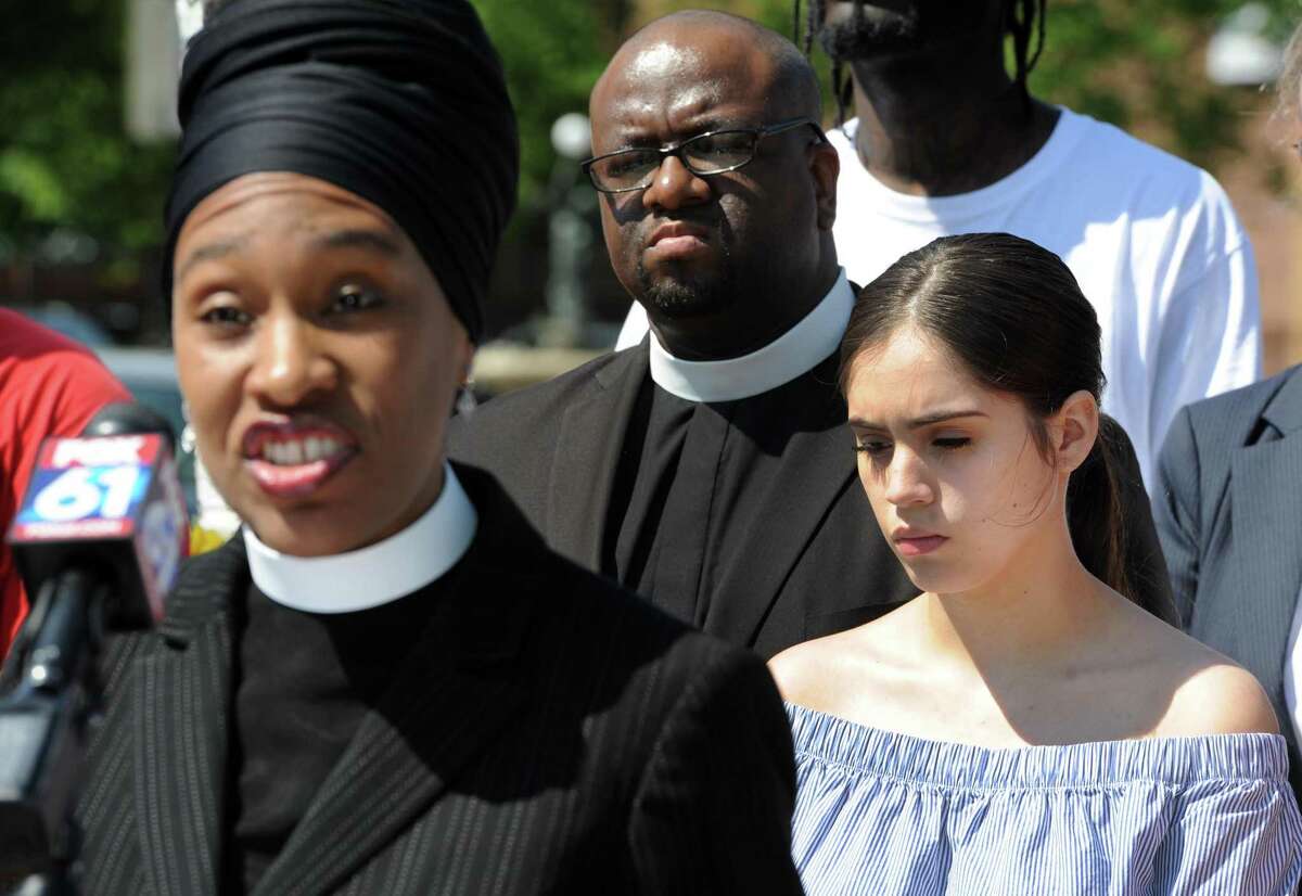 The Rev. Teddy Hickman-Maynard of Bethel AME Church, center, and Jayson Negron's half-sister Jazmarie Melendez, right, listens to The Rev. Bernadette Hickman-Maynard of Bethel AME Church speaks to others gathered at the site of Negron's shooting on Fairfield Avenue in Bridgeport, Conn. CONECT clergy and lay leaders called for a more public investigation during a press conference on Friday, June 2, 2017.