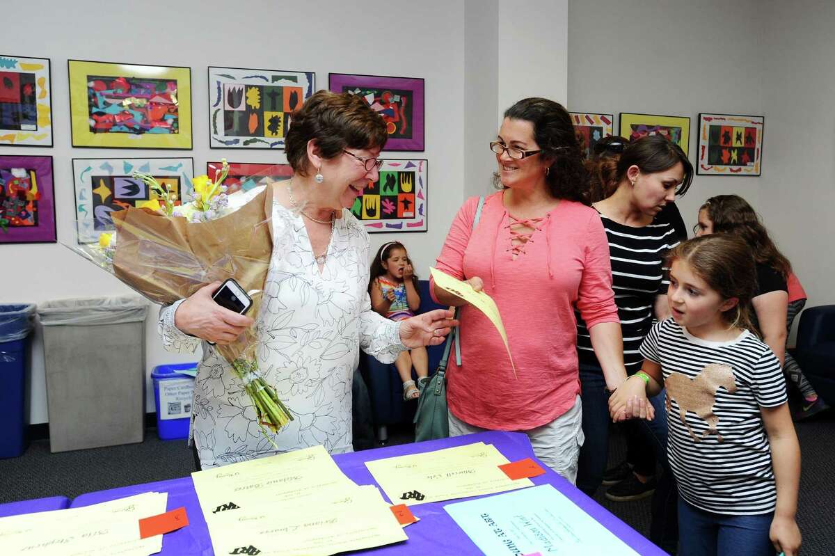 Springdale art teacher Susan Ramsey, left, hands a certificate to one of her students during a special art exhibit at the University of Bridgeport's Stamford campus in Stamford, Conn. on Wednesday, May 31, 2017. Ramsey is retiring at the end of the year after a 42-year career in the district.