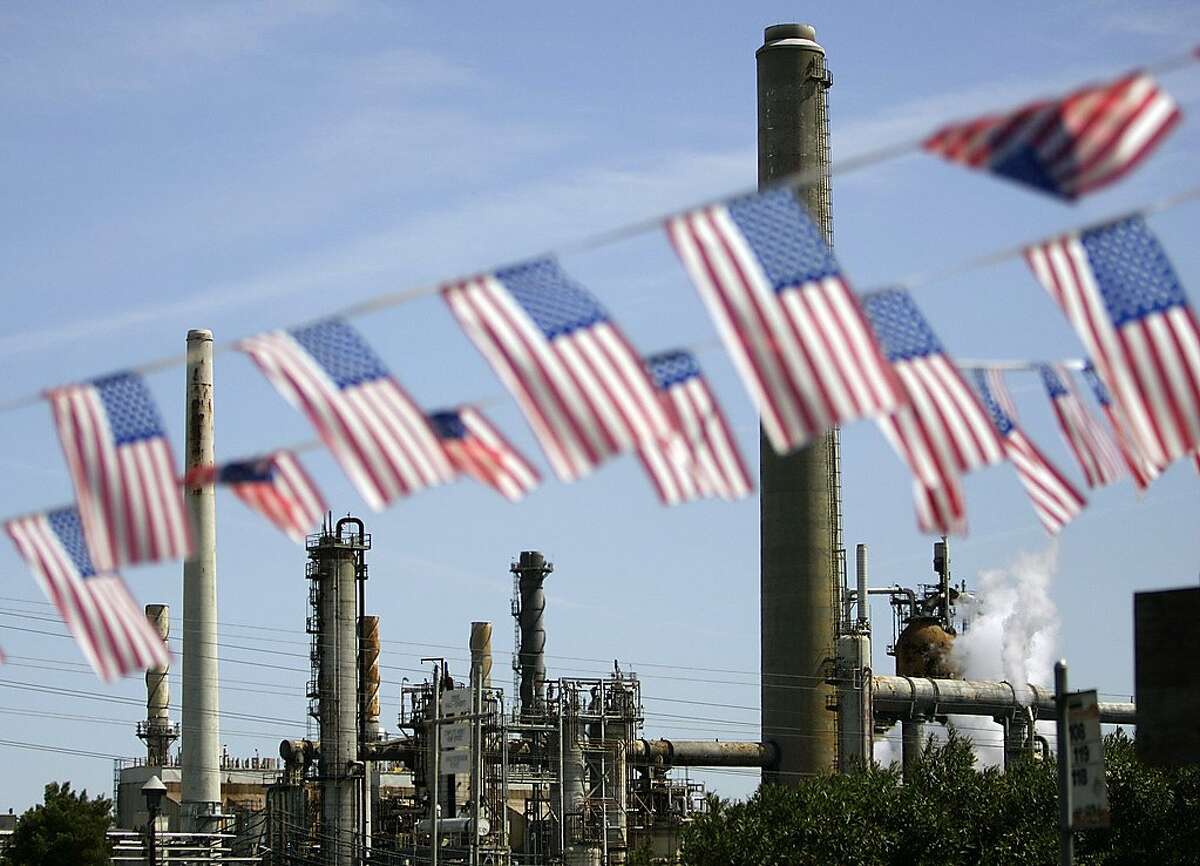 In this April 30, 2008 file photo, American flags are seen near the Shell refinery, in Martinez, Calif. On Weds., Nov. 14, 2012, California’s largest greenhouse gas emitters will for the first time begin buying permits in a landmark "cap-and-trade" system meant to control emissions of heat-trapping gases and spur investment in clean technologies. The program is a key part of California’s 2006 climate-change law, AB32, a suite of regulations that dictate standards for cleaner-burning fuels, more efficient automobiles and increased use of renewable energy. (AP Photo/Ben Margot, File)