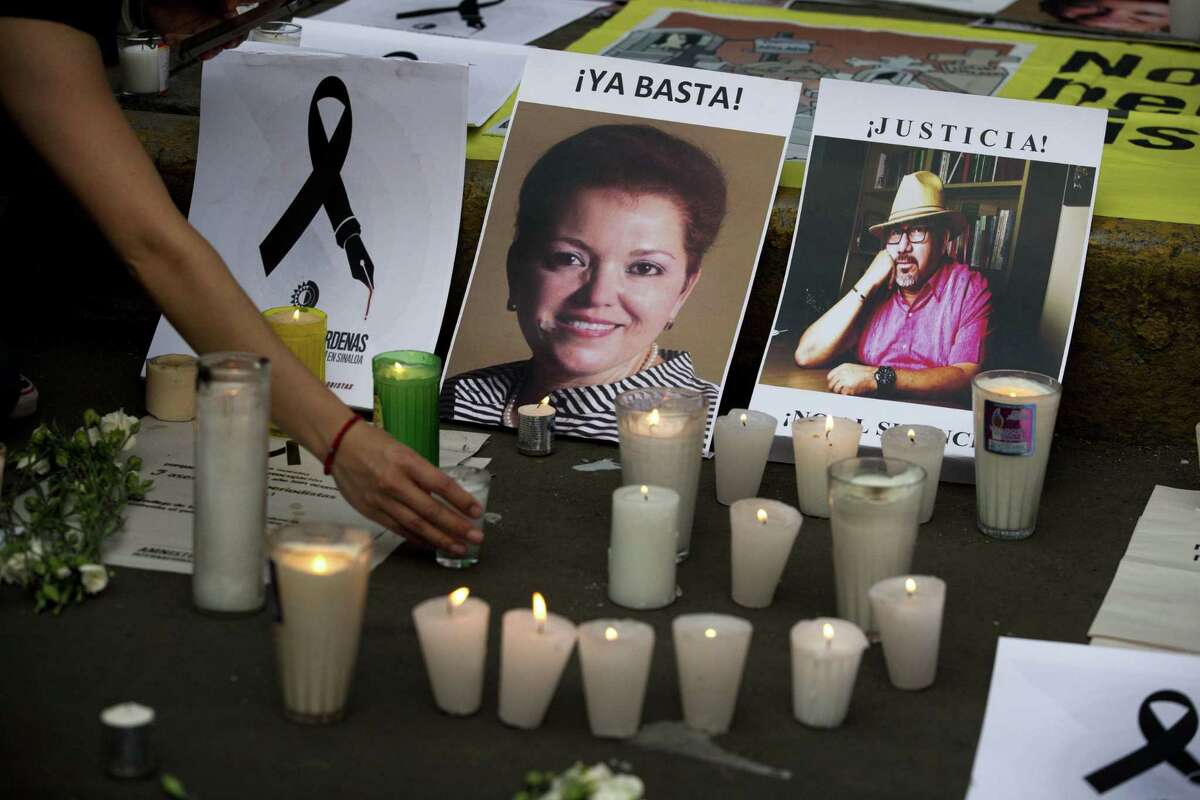 A woman places a candle in front of pictures of murdered journalists Miroslava Breach, left, and Javier Valdez during a demonstration last month against the killing of journalists, outside the Interior Ministry in Mexico City. These killings threaten Mexico’s institutions.
