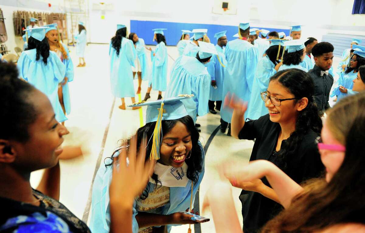 Friends use their hands to help cool of graduate Benedicte Kabongo before the start of Kolbe Cathedral's Class of 2017 Commencement Exercises at St. Augustine Cathedral in Bridgeport, Conn., on Thursday June 1, 2017.