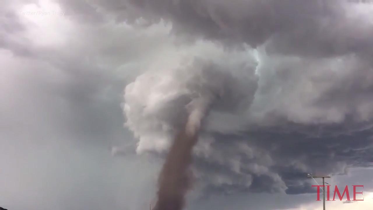 Photo shows man casually mowing the lawn with massive tornado nearby