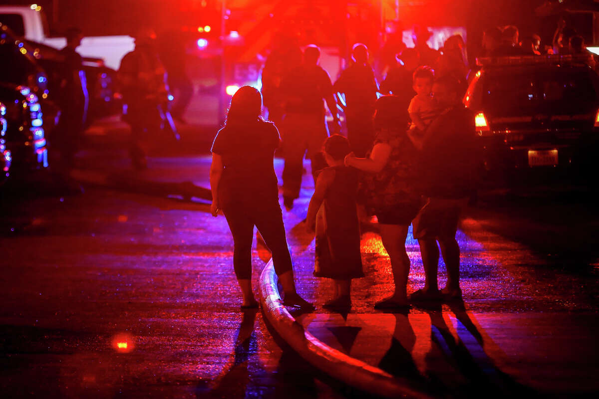 Residents, both displaced and neighbors, gather to comfort one another in the streets of Autumnwood Apartments as firefighters continue to battle a fire, believed to have been sparked by lightning, that destroyed multiple apartments units on Saturday, June 3, 2017, in Conroe.