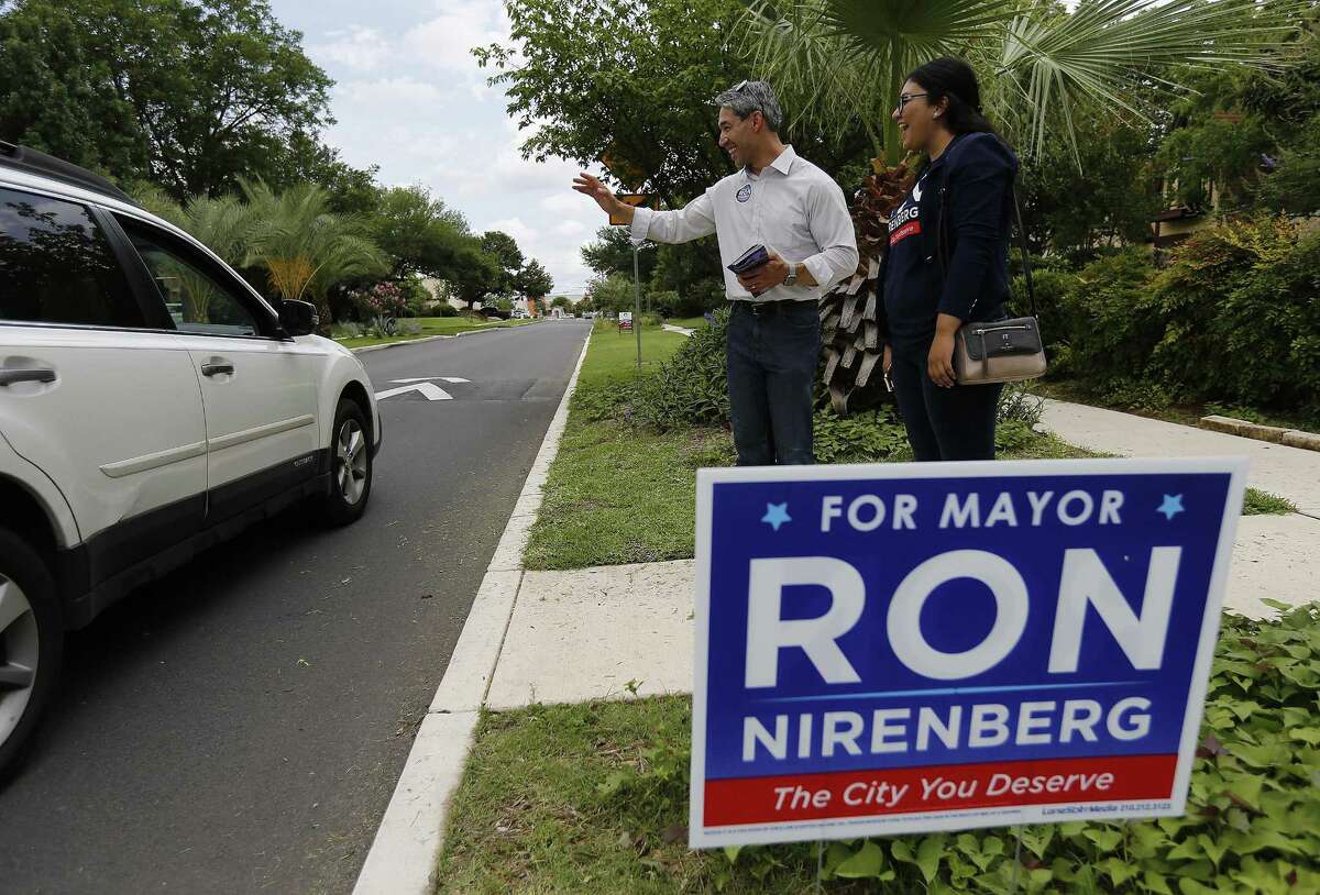 District 8 Councilman Ron Nirenberg, with deputy campaign manager Juany Torres, waves to a motorist.