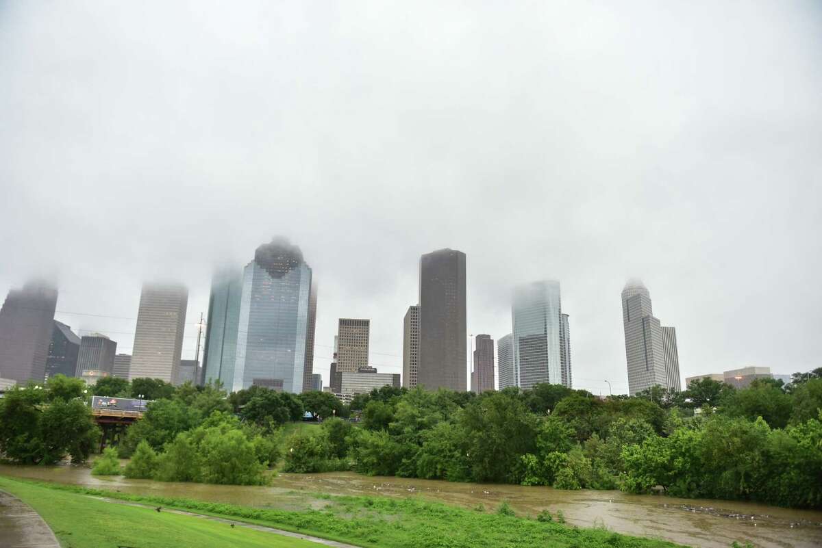 The view from a rising Buffalo Bayou Sunday afternoon saw rain clouds covering the tops of some downtown Houston buildings.