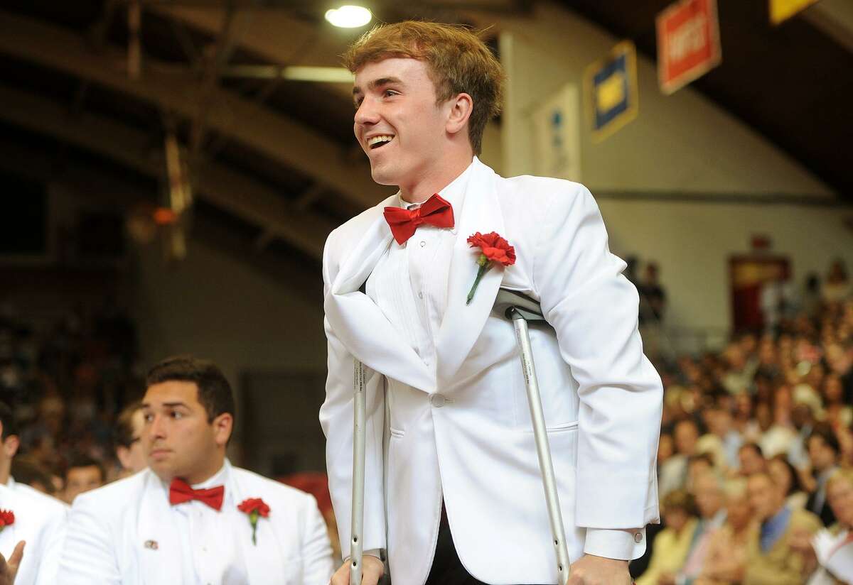 Graduate and Senior Class President Kevin P. Gallagher Jr. walks on crutches to receive an award during Fairfield Prep's 75th Commencement Exercises at Fairfield University's Alumni Hall on Sunday.