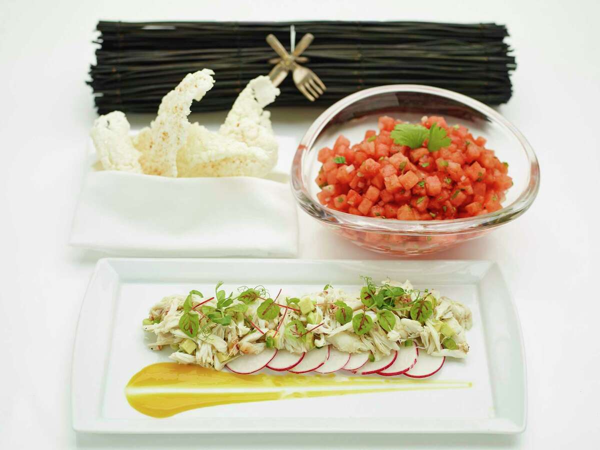 Avocado and Crab Salad is garnished with sliced radish and citrus-mango sauce, foreground; a chilled Watermelon Salad, upper right, is served with deep-fried rice crisps.