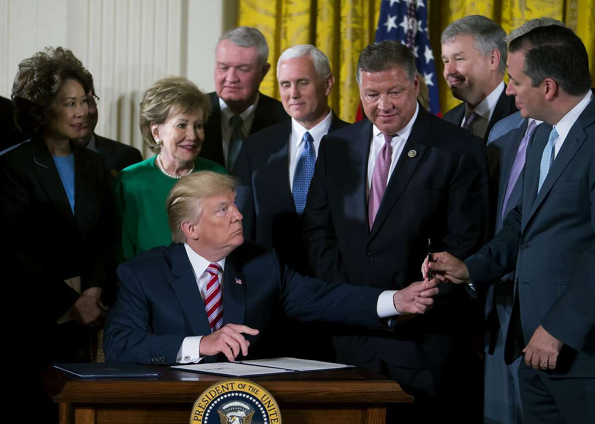 U.S. President Donald Trump, seated, hands a pen to Senator Ted Cruz, a Republican from Texas, right, after signing the Air Traffic Control Reform Initiative during a press conference in the East Room of the White House in Washington, D.C., U.S., on Monday, June 5, 2017. Trump on Monday unveiled his proposal to hand over control of the U.S. air-traffic control system to a non-profit corporation, calling the current system an antiquated mess that doesn’t work and wastes money. Photographer: Eric Thayer/Bloomberg