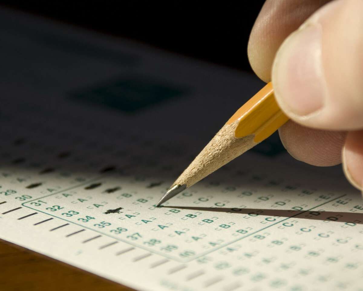 Extreme closeup in dramatic lighting of child's hand marking standardized test form.