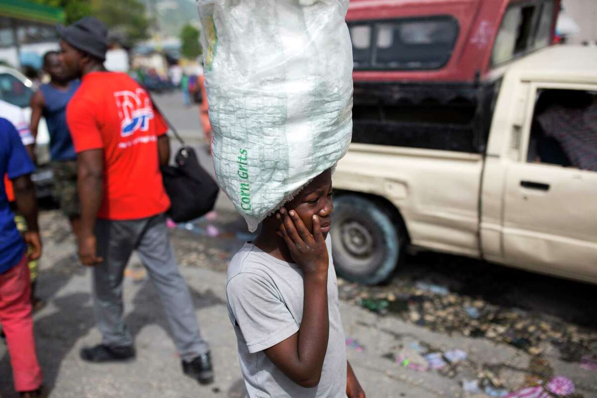 Watson Saint Fleur, 12, carries water for sale in ﻿a suburb of Port-au-Prince, Haiti. Watson is unsure how he came to be a woman's servant. after his mother dies. d in hardship doing household chores and peddling plastic bags of drinking water along city streets noisy with motorbikes and trucks. (AP Photo/Dieu Nalio Chery)